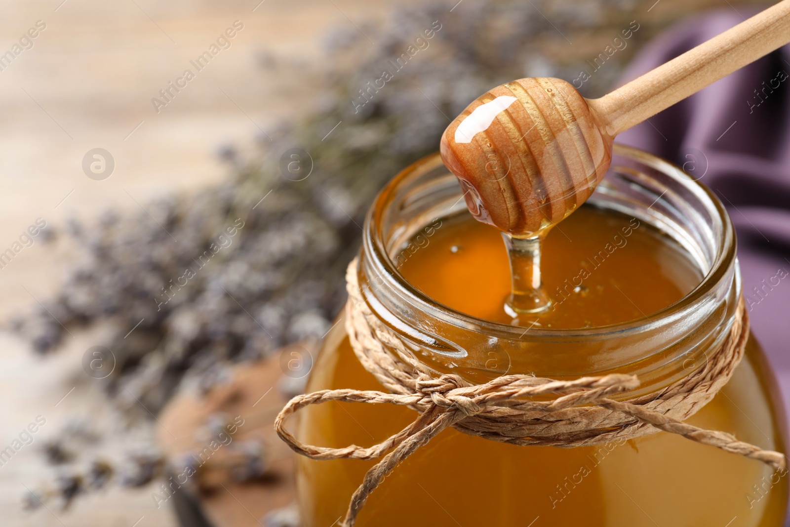 Photo of Tasty fresh sunflower honey with wooden dipper on table, closeup