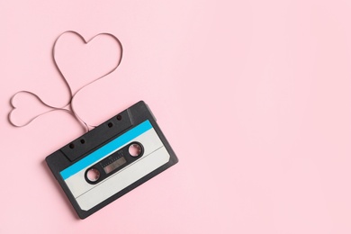 Photo of Top view of music cassette and hearts made with tape on pink background, space for text. Listening love song