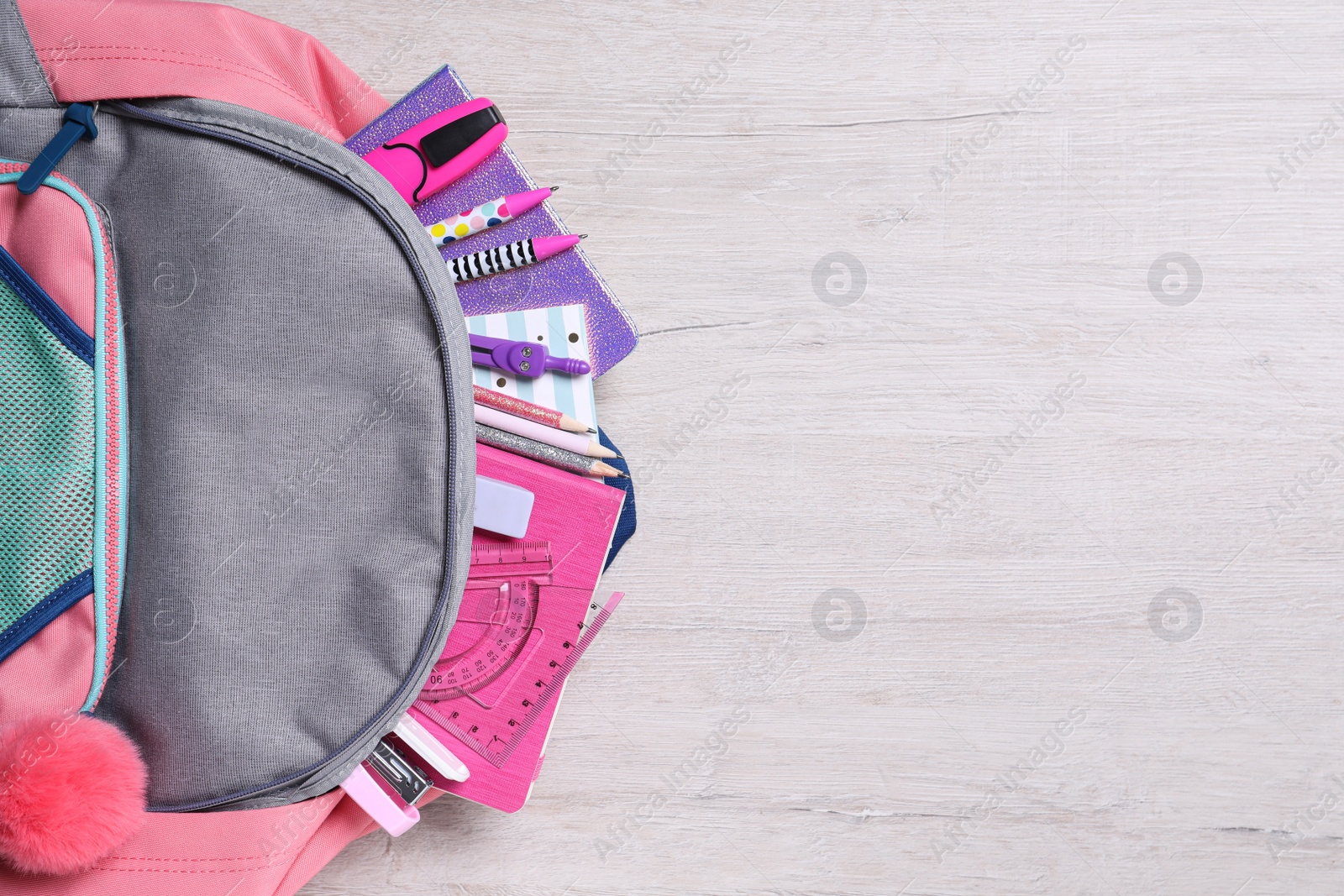 Photo of Backpack with different school stationery on wooden table, top view. Space for text