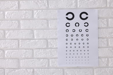 Photo of Vision test chart on white brick wall, space for text