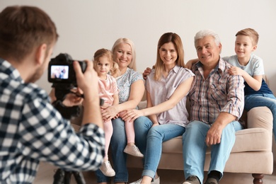 Professional photographer taking photo of family on sofa in studio