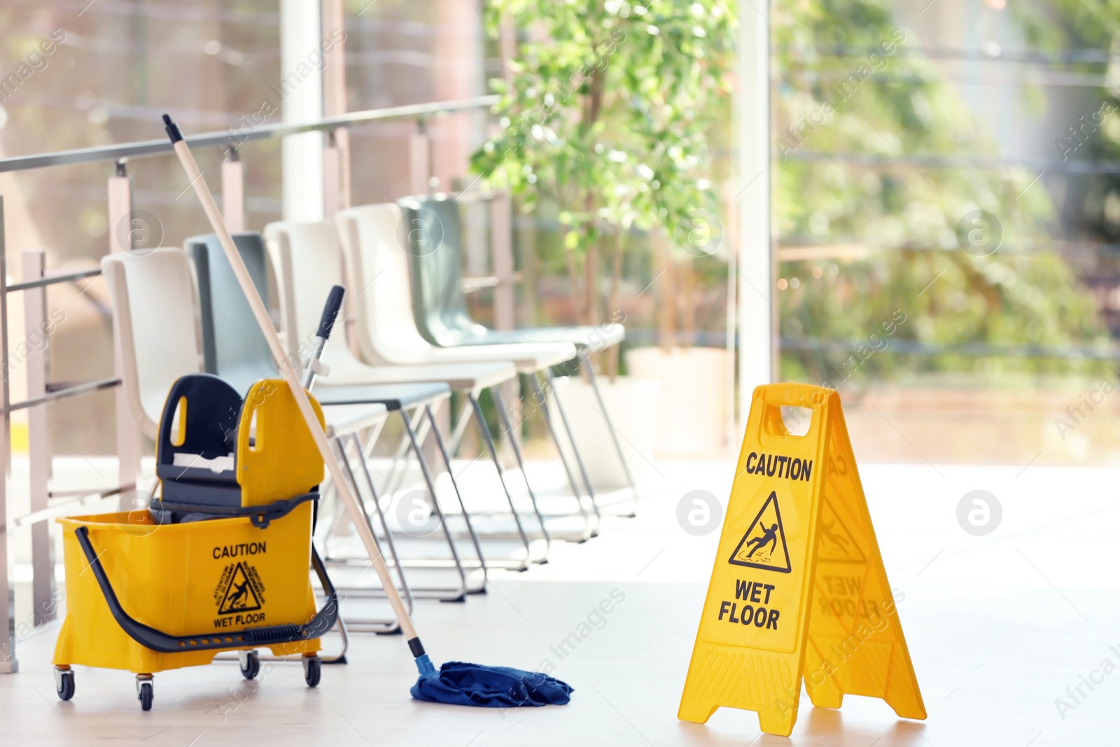 Photo of Safety sign with phrase Caution wet floor and mop bucket, indoors. Cleaning service