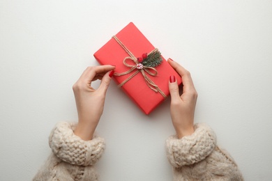 Photo of Woman holding Christmas gift box on white background, top view