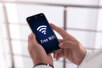 Image of Man using mobile phone connected to WiFi indoors, closeup