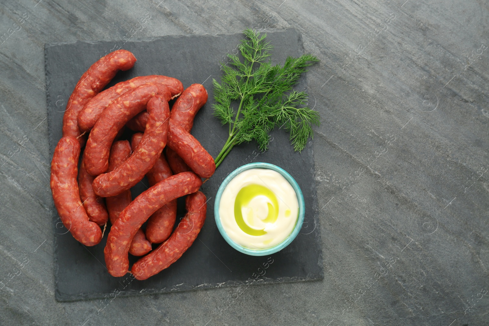 Photo of Tasty sausages, sauce and dill on black table, top view with space for text. Meat product