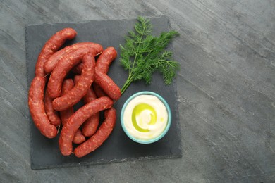 Tasty sausages, sauce and dill on black table, top view with space for text. Meat product