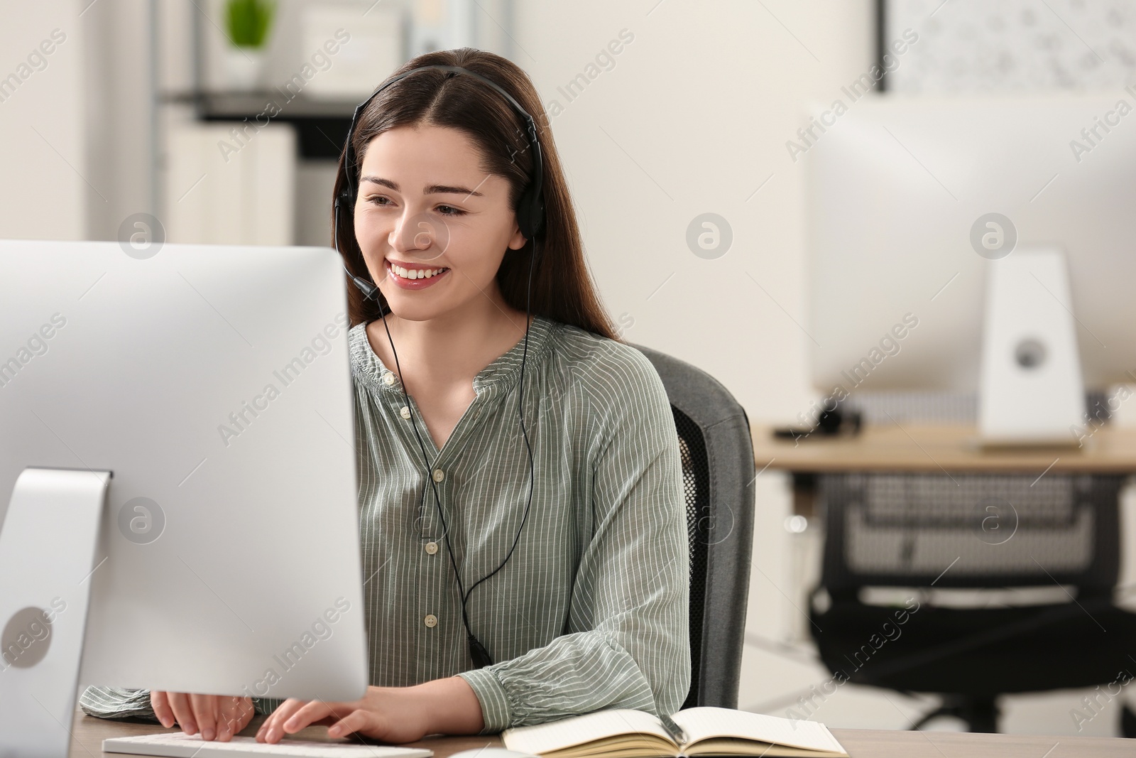 Photo of Hotline operator with headset working on computer in office. Space for text