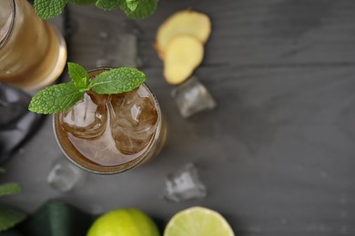 Photo of Glass of tasty ginger ale with ice cubes and mint on grey wooden table, top view. Space for text