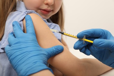 Doctor giving injection to little girl in hospital, closeup. Immunization concept