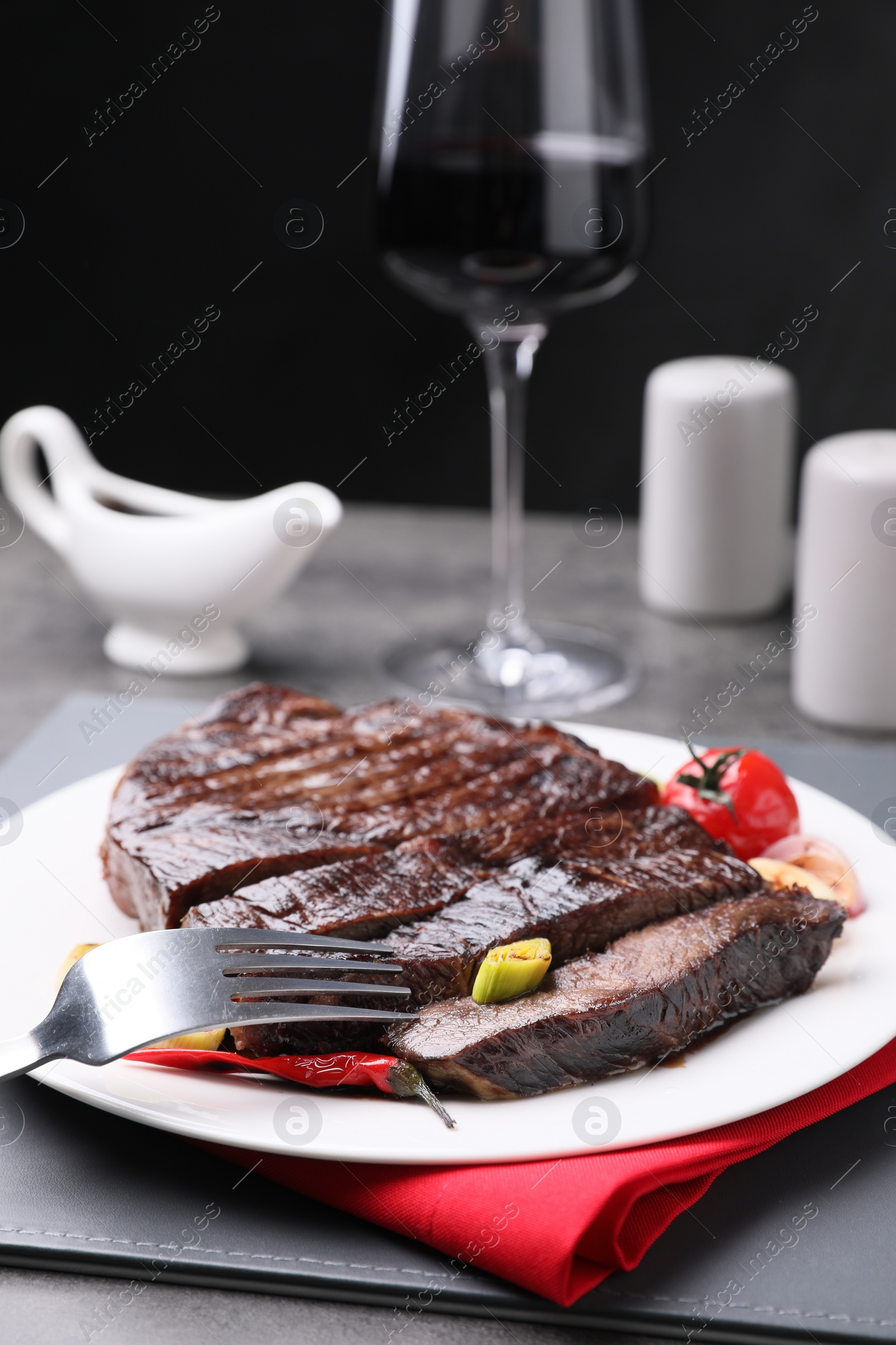 Photo of Delicious grilled beef meat served on grey table, closeup