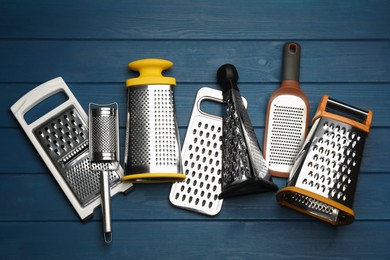 Different modern graters on blue wooden table, flat lay