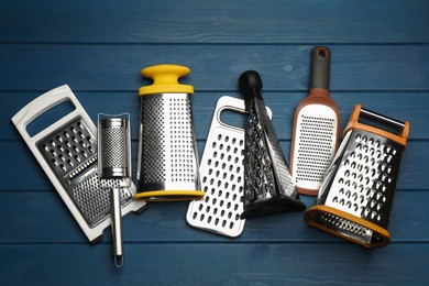 Photo of Different modern graters on blue wooden table, flat lay