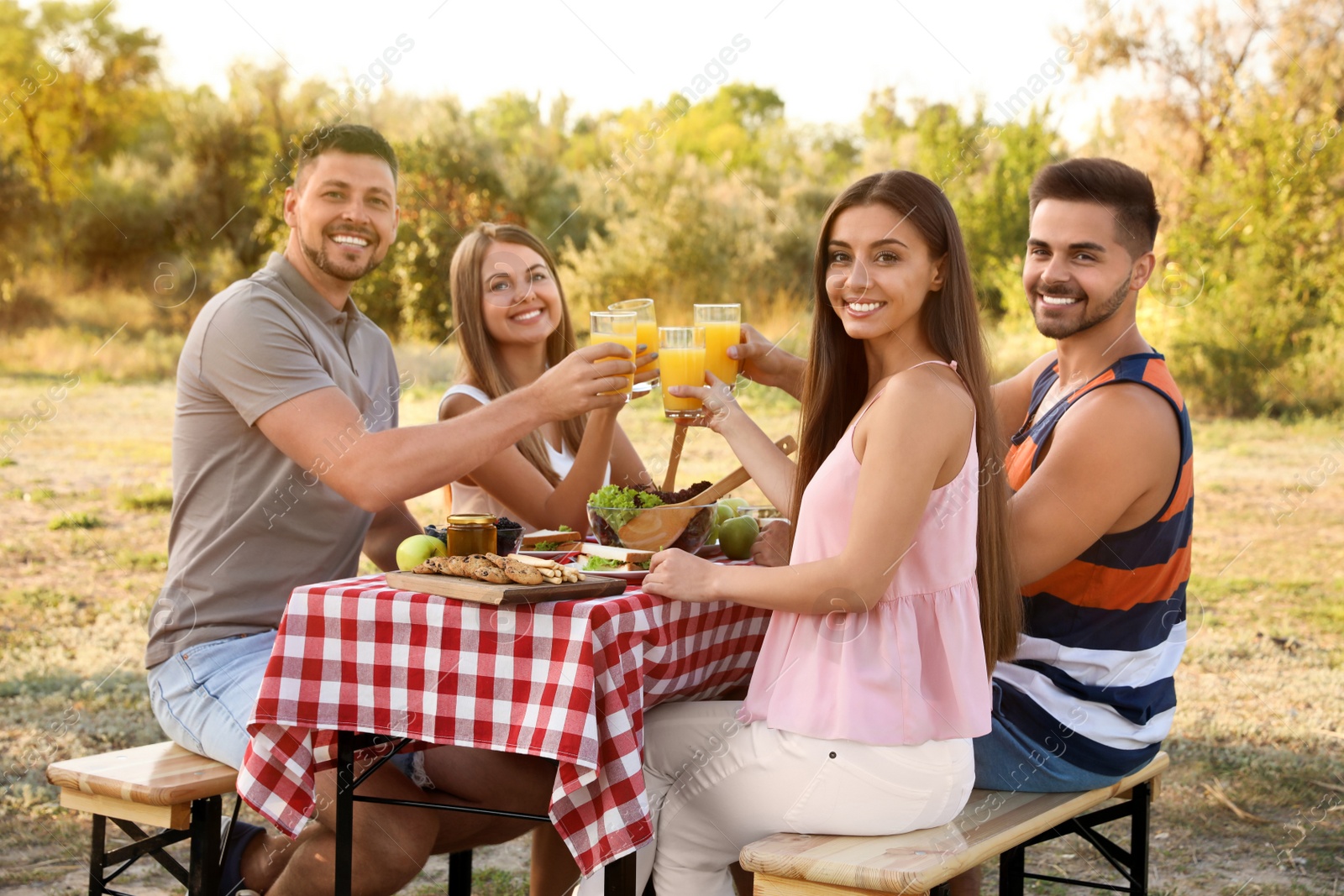 Photo of Happy young people having picnic at table in park