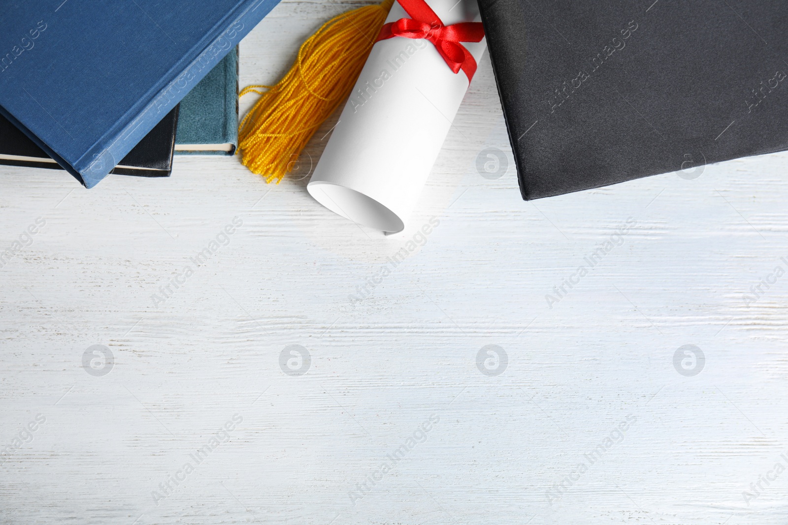 Photo of Flat lay composition with graduation hat and student's diploma on white wooden table, space for text