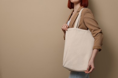 Woman with eco bag on beige background, closeup. Space for text