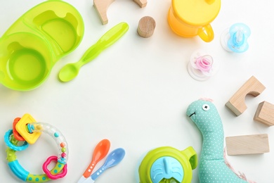 Flat lay composition with baby accessories and tableware for food on light background