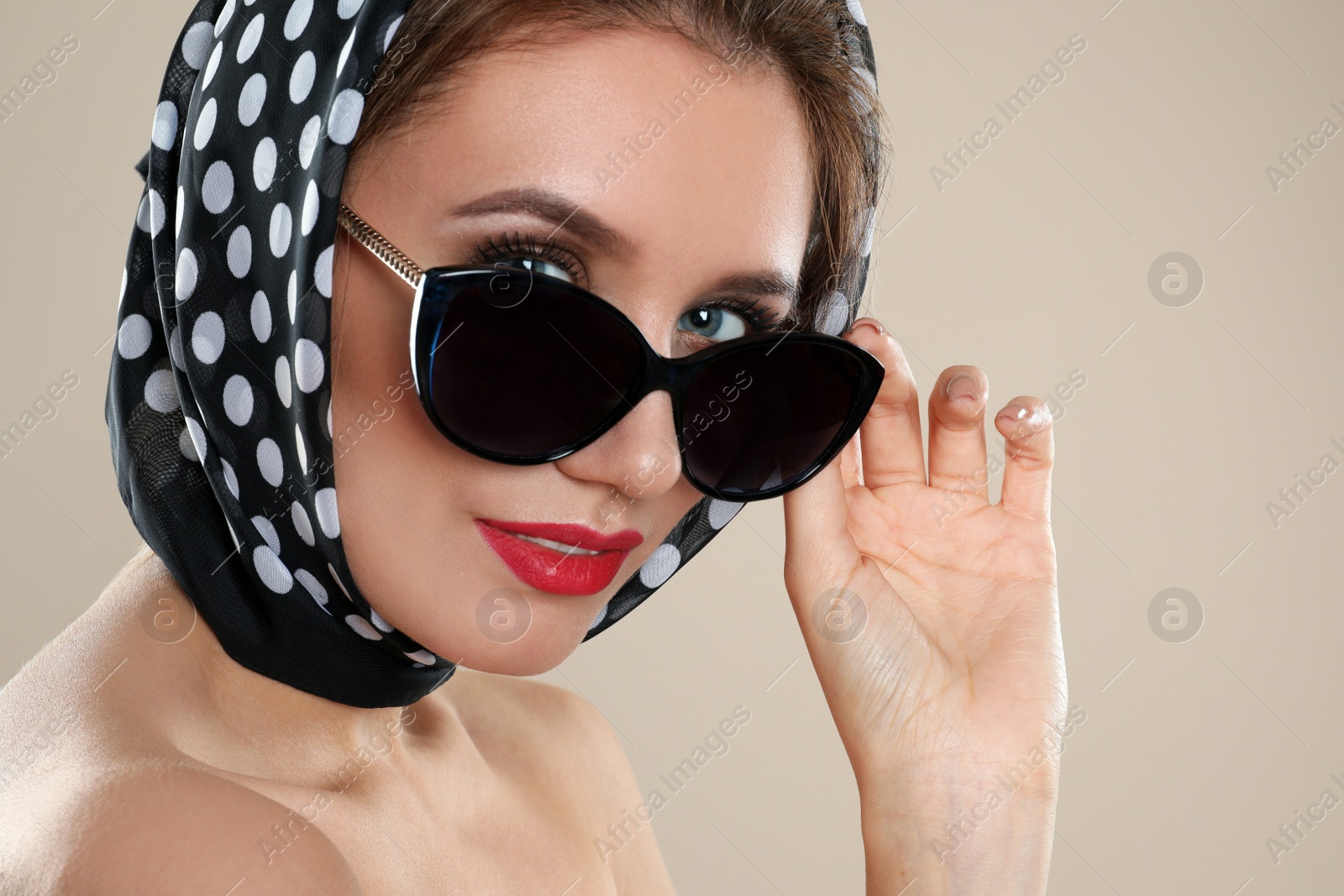 Photo of Young woman wearing stylish sunglasses and headscarf on beige background