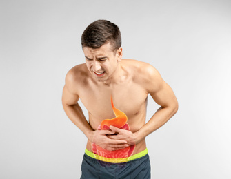 Young man suffering from abdominal pain on light background