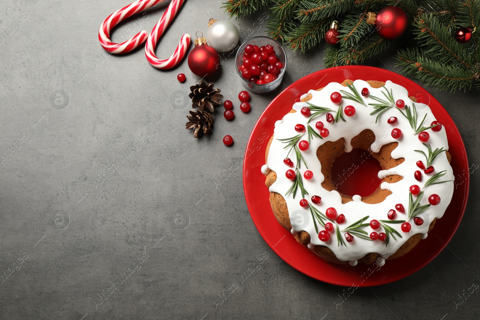 Photo of Flat lay composition with traditional Christmas cake and decorations on grey table, space for text