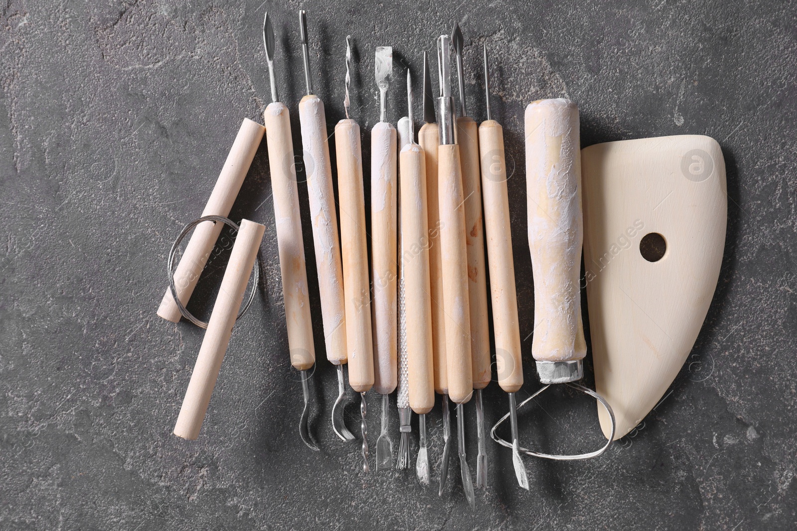 Photo of Set of different clay crafting tools on grey table, top view