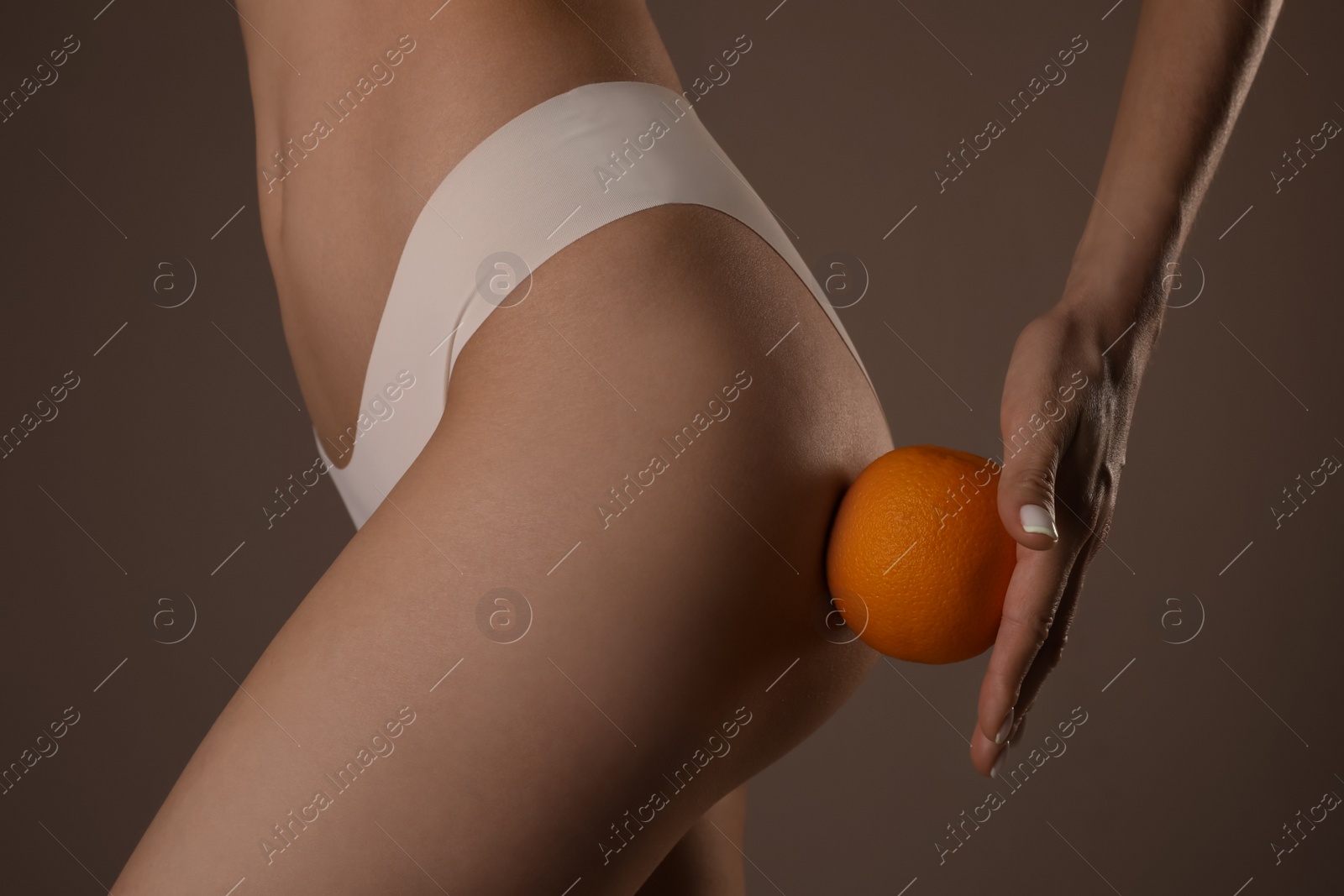 Photo of Closeup view of slim woman in underwear with orange on beige background. Cellulite problem concept