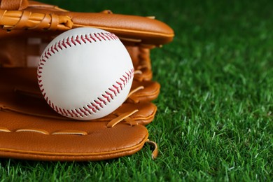 Photo of Catcher's mitt and baseball ball on green grass, closeup with space for text. Sports game