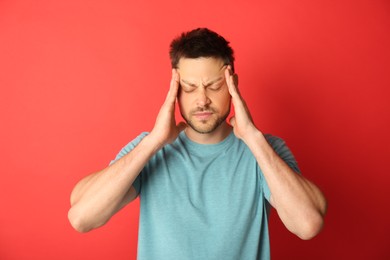 Photo of Man suffering from terrible migraine on red background