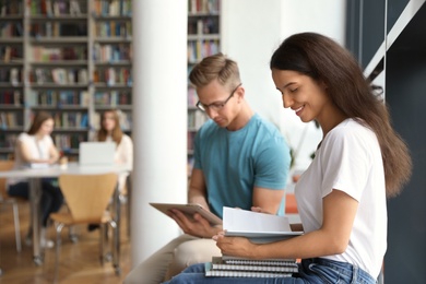 Photo of Happy young people studying in library. Space for text