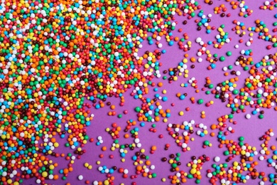 Photo of Colorful sprinkles on purple background, flat lay. Confectionery decor