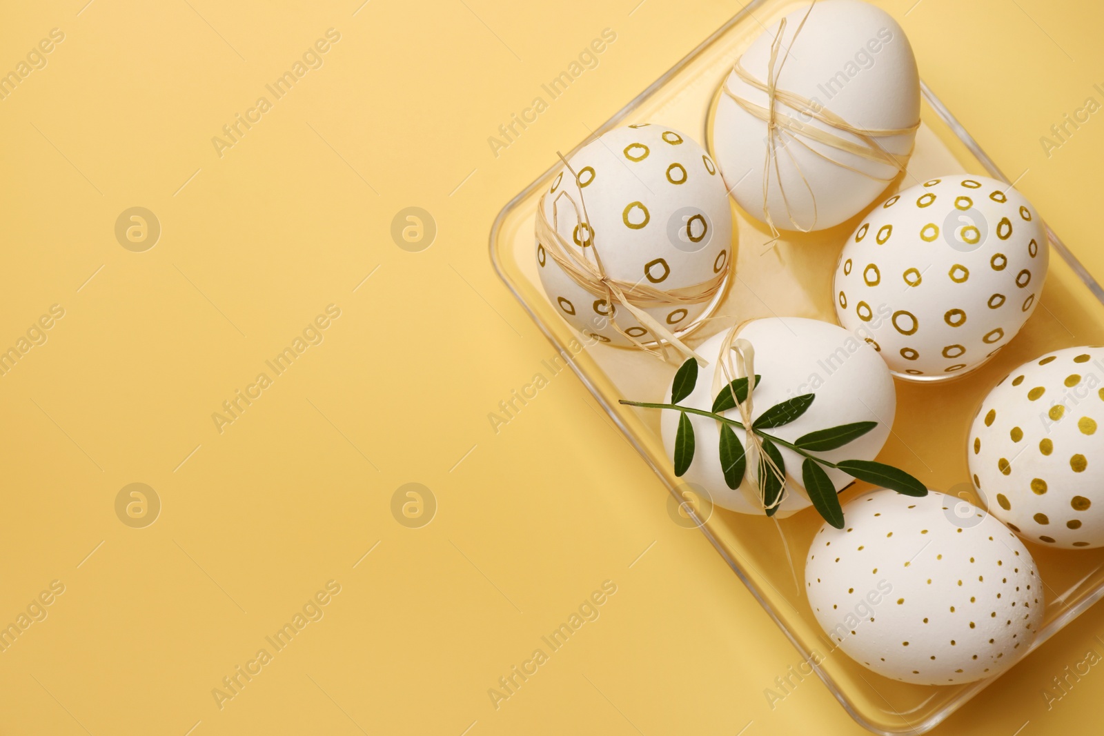 Photo of Festively decorated chicken eggs on yellow background, top view with space for text. Happy Easter