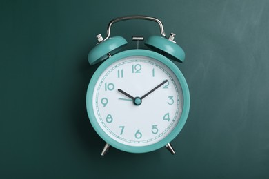 Alarm clock on green chalkboard, top view. School time