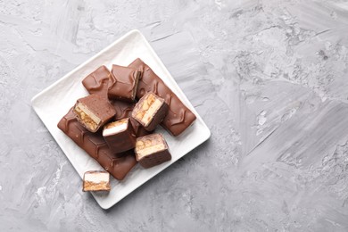 Photo of Tasty chocolate bars with nougat on gray textured table, top view. Space for text