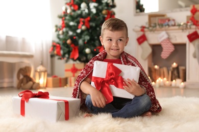 Photo of Cute little child with Christmas gift boxes at home