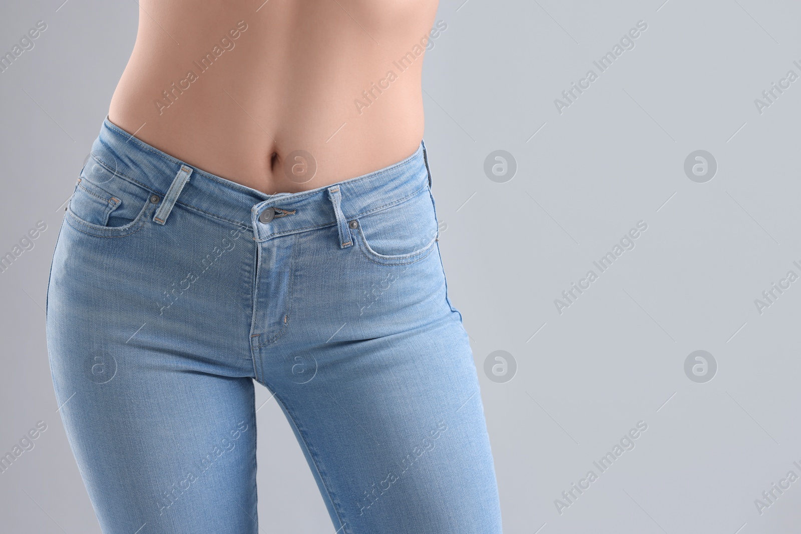 Photo of Woman wearing stylish jeans on light gray background, closeup. Space for text