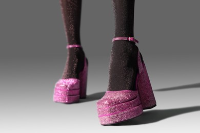 Woman wearing pink high heeled shoes with platform and square toes on light grey background, closeup