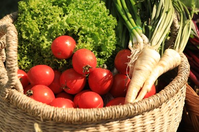 Different fresh ripe vegetables in wicker basket outdoors, closeup