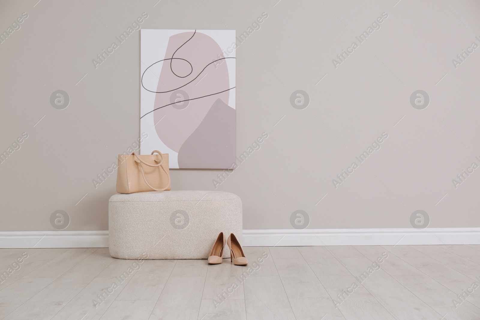 Photo of Stylish pouf with bag and shoes near beige wall indoors. Space for text