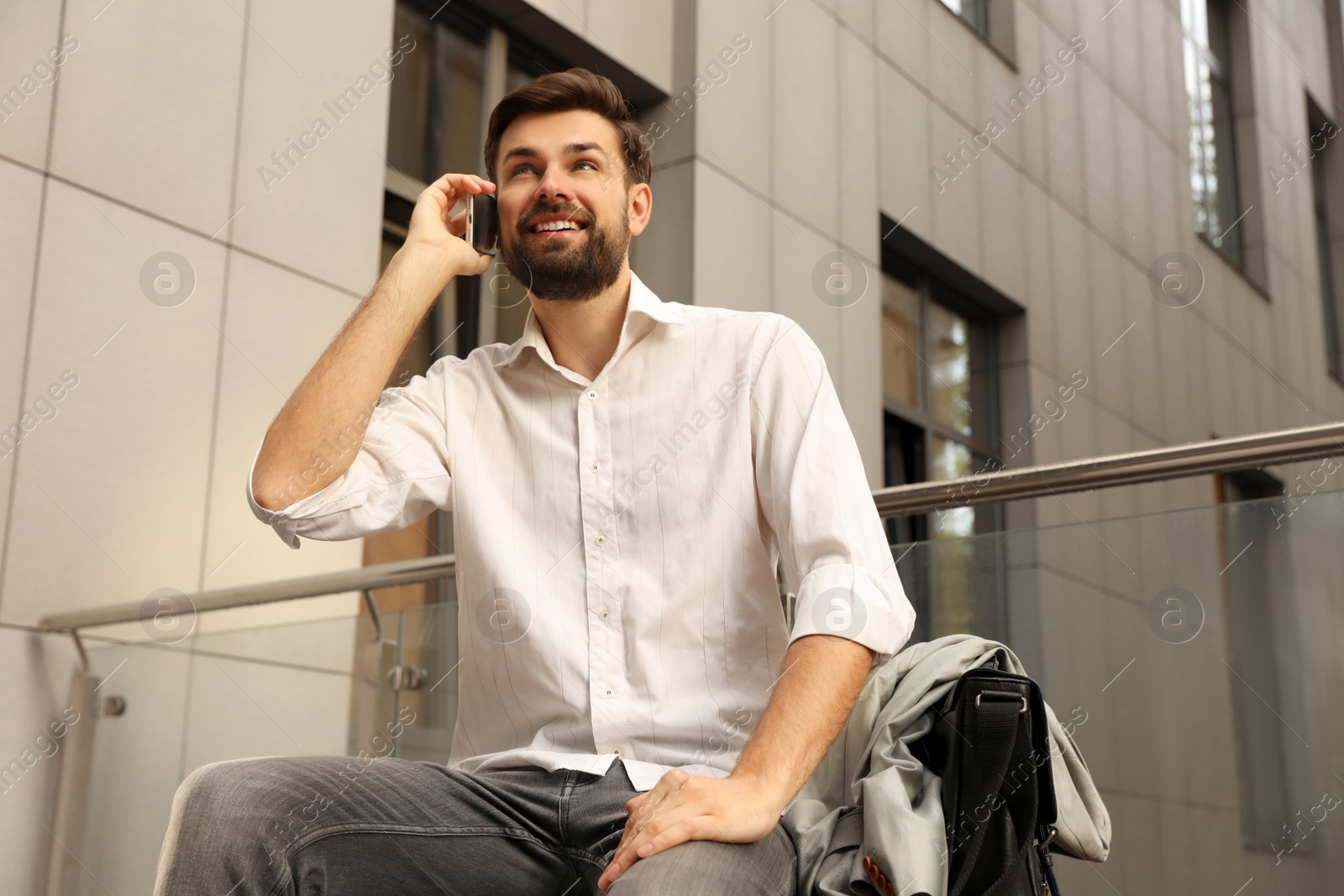 Photo of Handsome man talking on phone in modern city