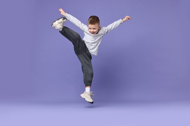 Happy little boy dancing on violet background. Space for text