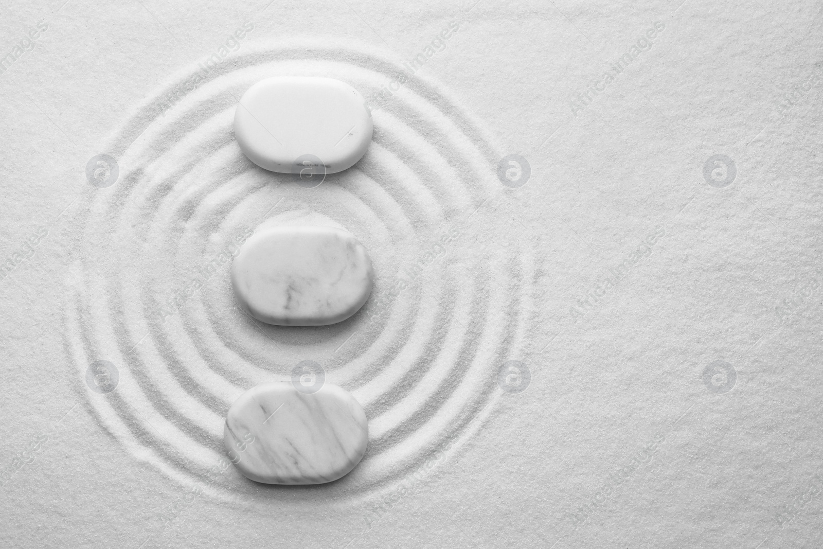 Photo of White stones on sand with pattern, flat lay. Zen, meditation, harmony