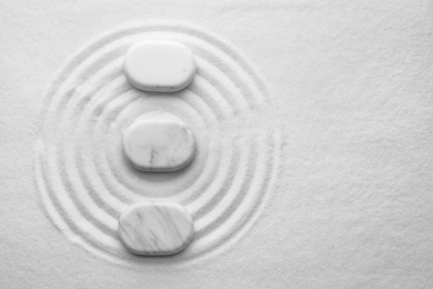 Photo of White stones on sand with pattern, flat lay. Zen, meditation, harmony