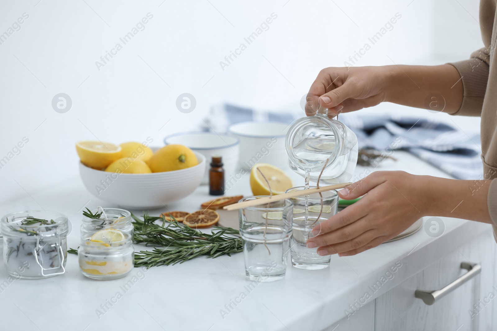 Photo of Woman making natural mosquito repellent candles at white table, closeup