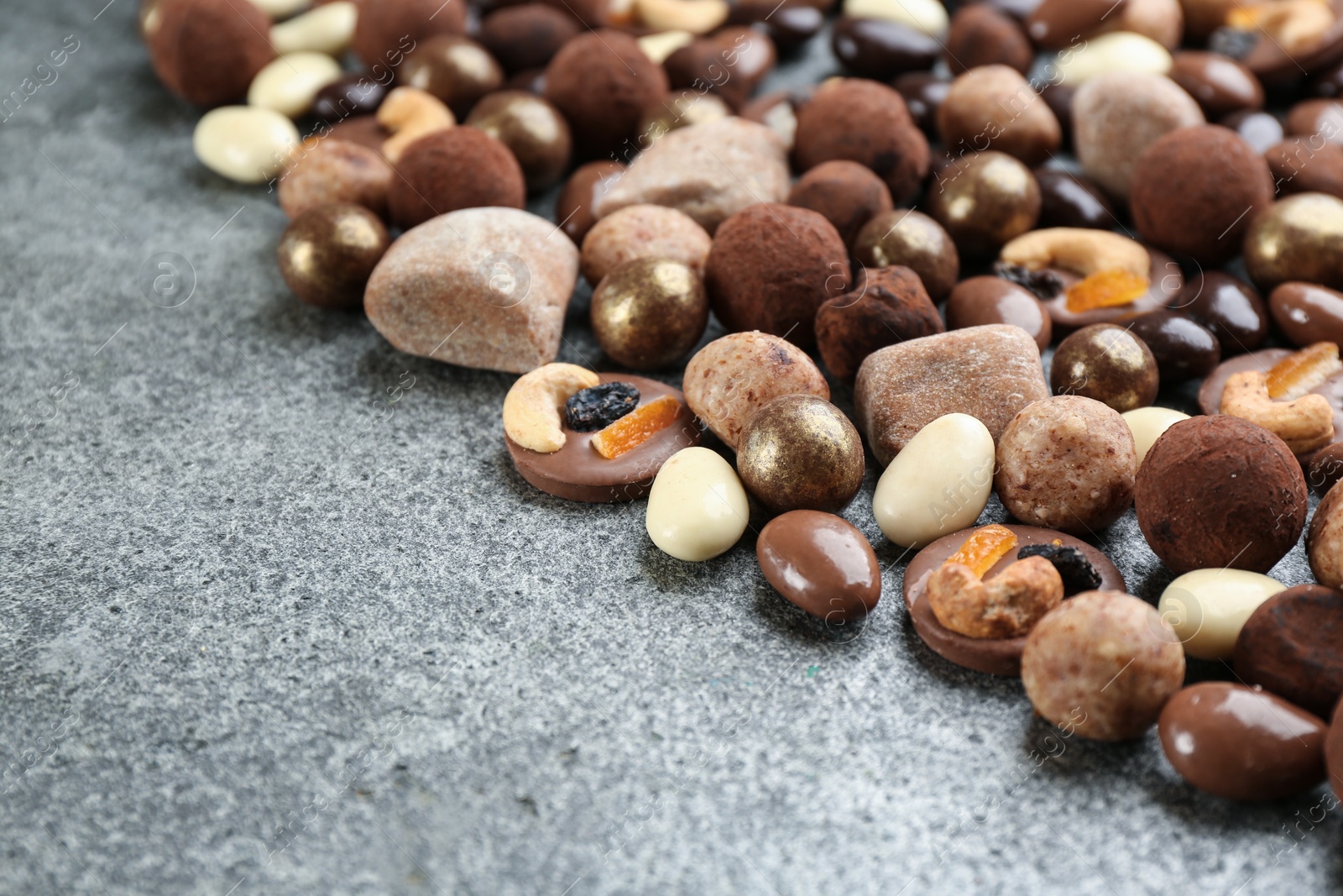 Photo of Different delicious chocolate candies on grey table, closeup