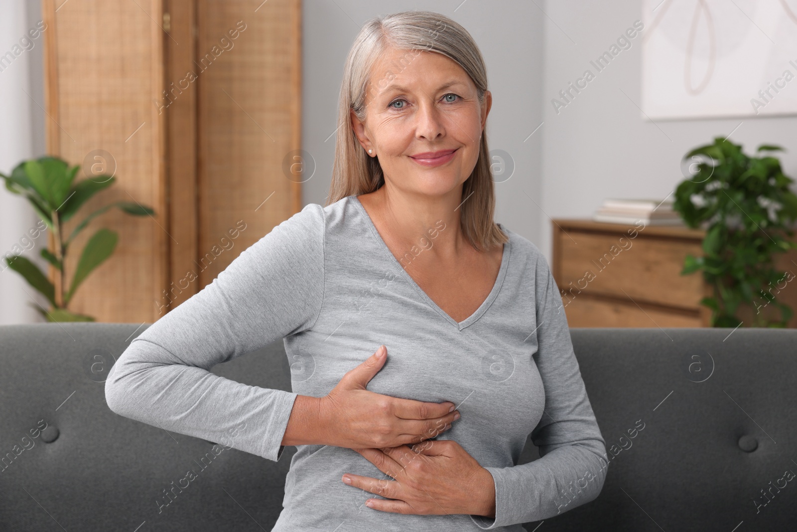 Photo of Beautiful senior woman doing breast self-examination at home