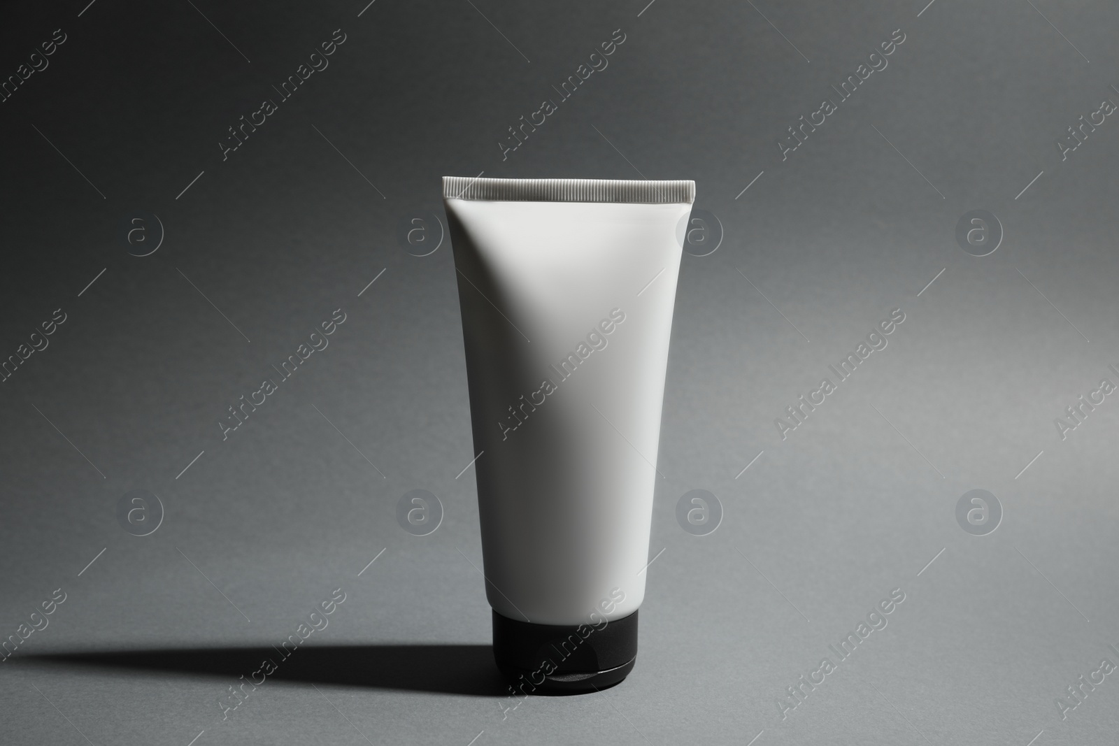 Photo of Tube of men's facial cream on grey background. Mockup for design