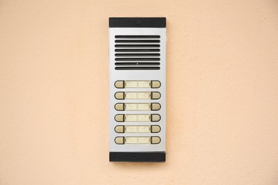 Photo of Modern intercom on beige wall. Security system