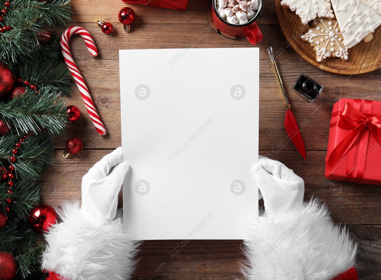 Photo of Santa Claus with letter and Christmas decor at wooden table, top view. Space for text