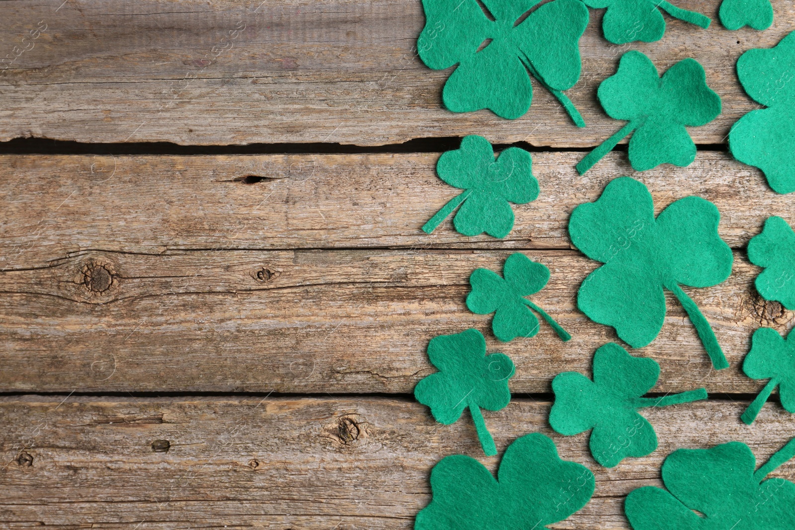 Photo of St. Patrick's day. Decorative clover leaves on wooden background, flat lay. Space for text