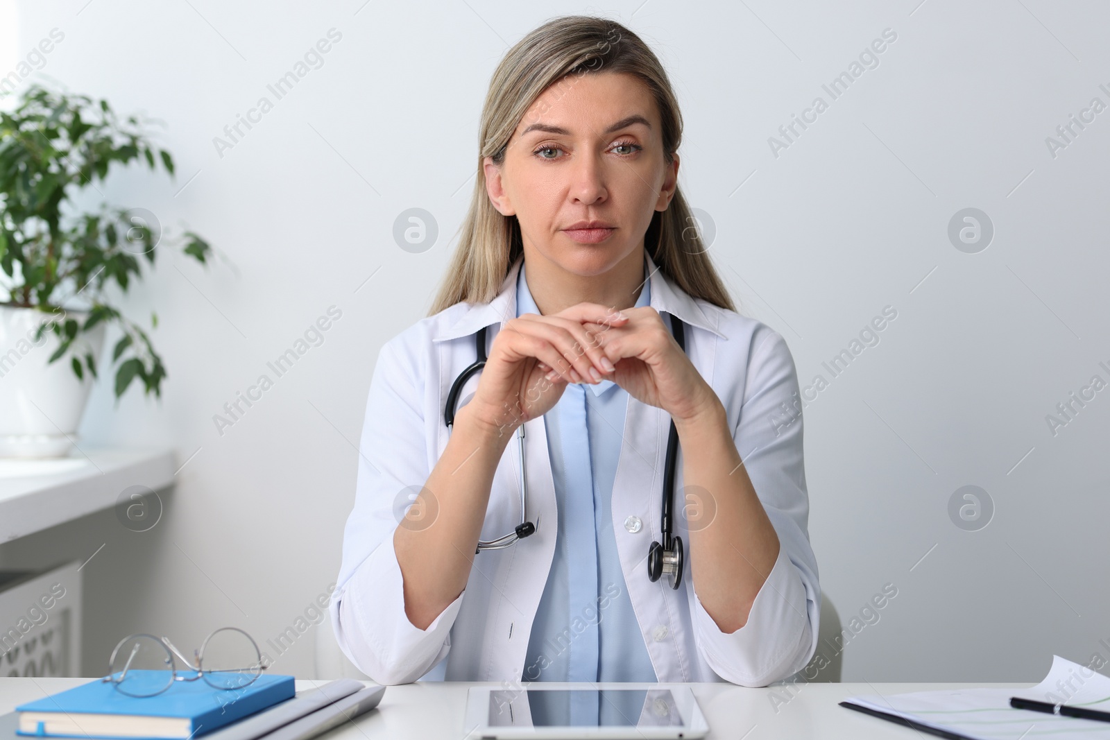 Photo of Portrait of happy doctor with stethoscope at white table in hospital