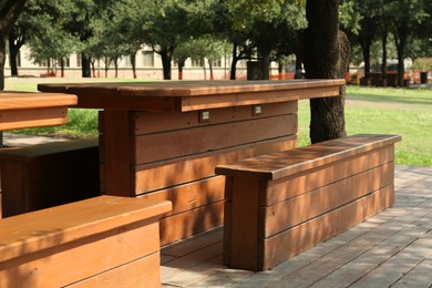 Photo of Empty wooden tables with benches in park